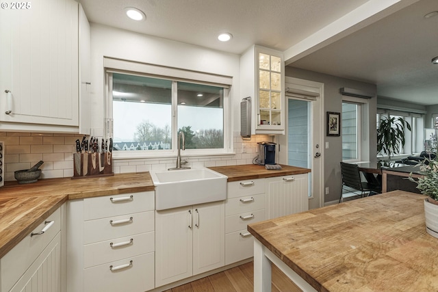 kitchen with wood counters, white cabinetry, and sink