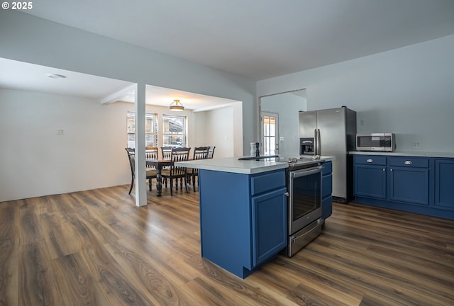 kitchen with blue cabinets, stainless steel appliances, and dark hardwood / wood-style floors