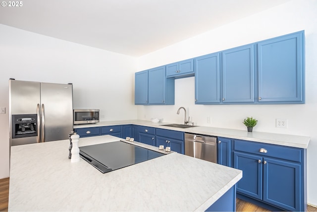 kitchen featuring stainless steel appliances, blue cabinets, light hardwood / wood-style floors, a center island, and sink