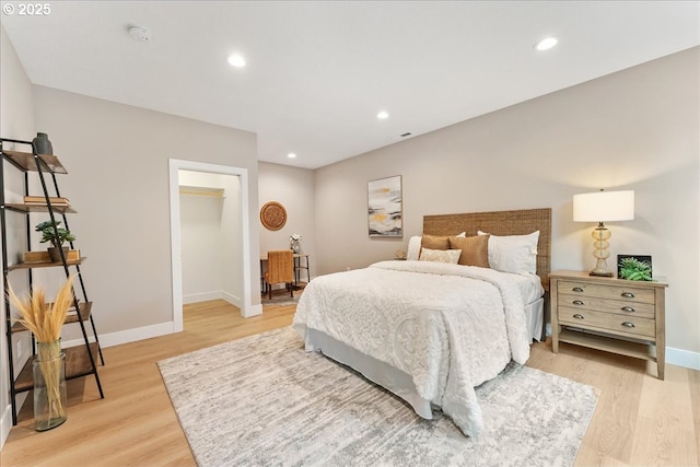 bedroom featuring a closet, a spacious closet, and light hardwood / wood-style flooring