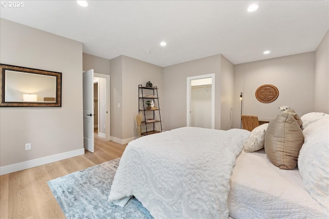 bedroom with a spacious closet and light hardwood / wood-style flooring