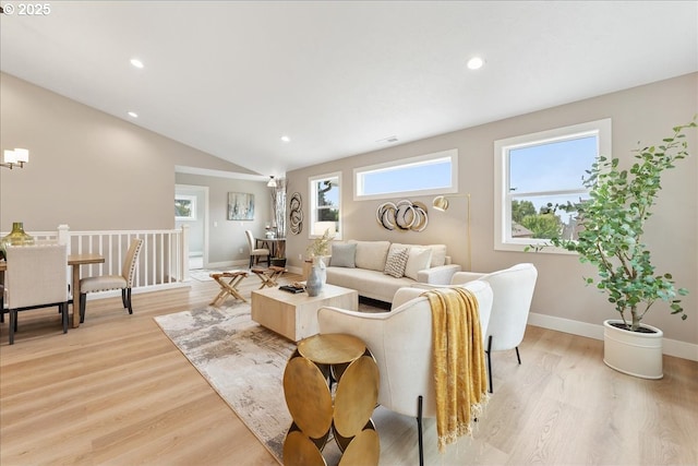 living room with lofted ceiling, an inviting chandelier, and light hardwood / wood-style flooring