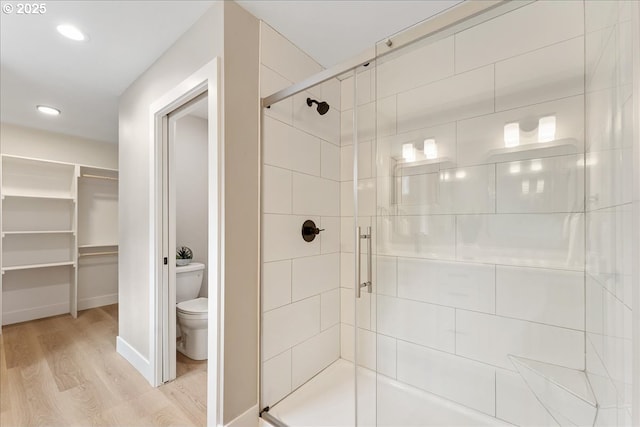 bathroom featuring hardwood / wood-style flooring, toilet, and walk in shower