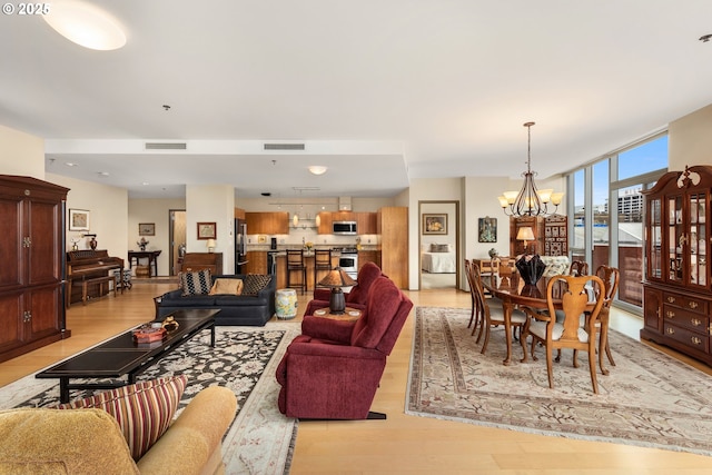 living area featuring light wood-type flooring, visible vents, and a chandelier