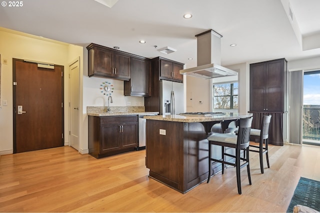 kitchen featuring appliances with stainless steel finishes, a barn door, light wood-style flooring, and island range hood