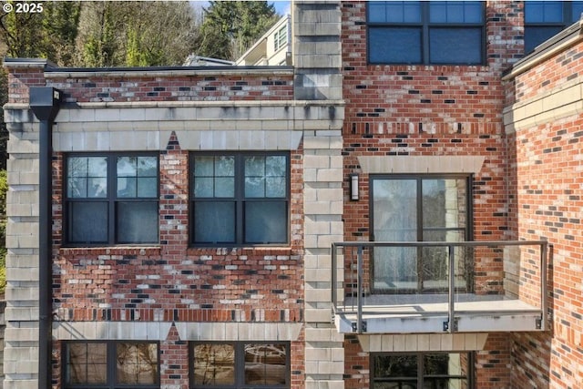 view of side of home featuring a balcony and brick siding