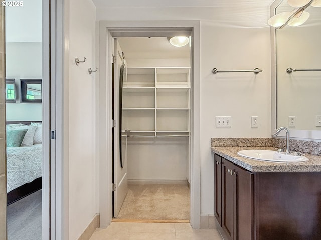 bathroom featuring ensuite bathroom, vanity, baseboards, a spacious closet, and tile patterned floors