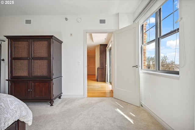 unfurnished bedroom featuring visible vents, light carpet, and baseboards