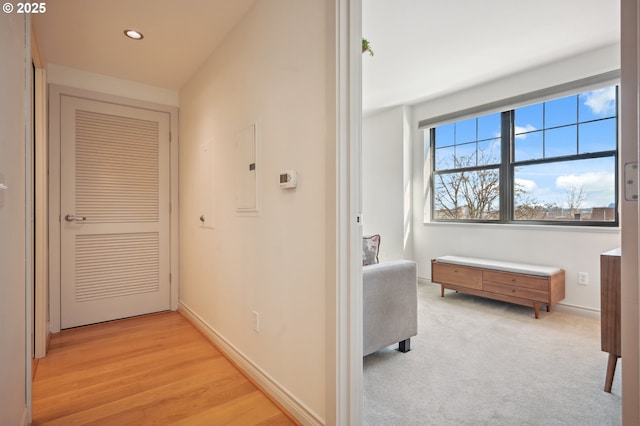 hall with light wood-style floors, recessed lighting, electric panel, and baseboards