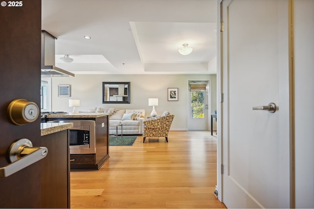 interior space featuring light wood-style floors, baseboards, a tray ceiling, and recessed lighting