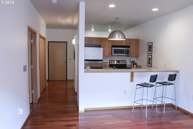 1125 NW 9th Ave, Portland, OR 97209 - kitchen with stainless steel appliances, dark wood-style floors, a kitchen bar, a peninsula, and recessed lighting