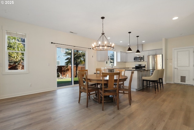 dining space with wood finished floors, visible vents, plenty of natural light, and an inviting chandelier