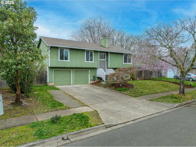 view of front of house with a front yard, fence, driveway, a chimney, and a garage