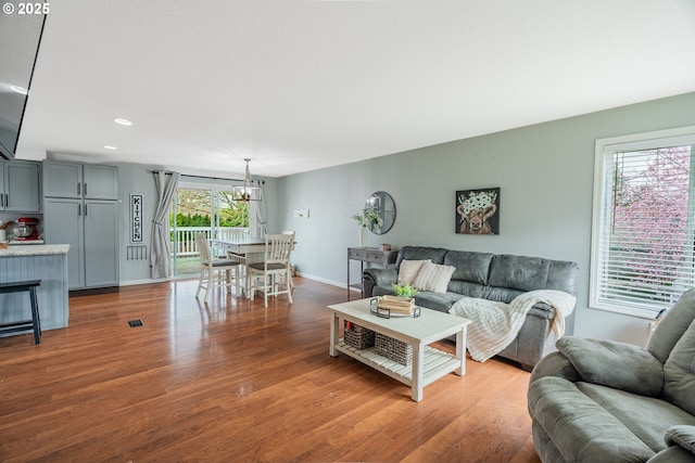 living area featuring a notable chandelier, recessed lighting, baseboards, and wood finished floors