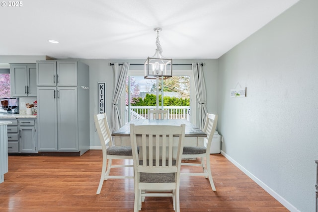 dining room featuring light wood finished floors, a chandelier, and baseboards