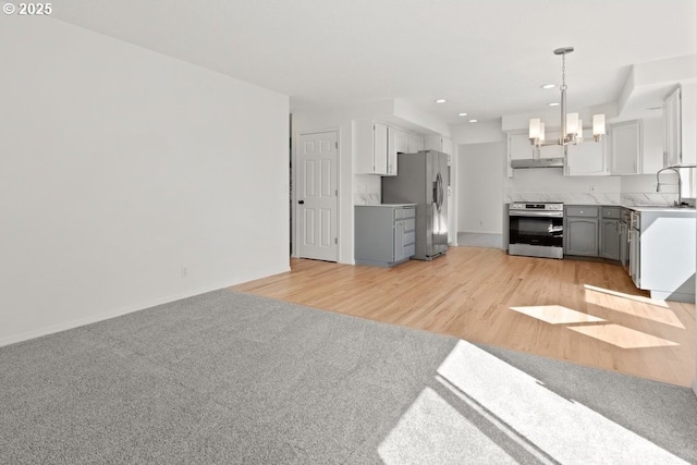 kitchen with appliances with stainless steel finishes, a sink, a notable chandelier, and gray cabinets