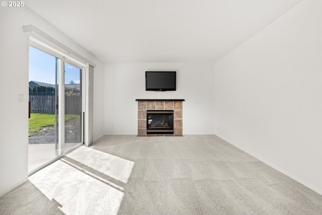 unfurnished living room featuring a tiled fireplace, baseboards, and carpet flooring