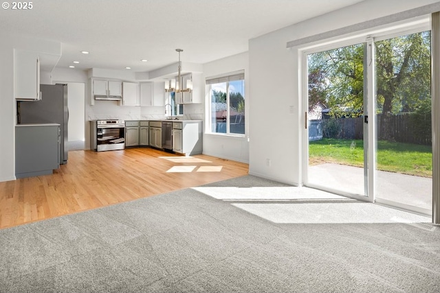 interior space featuring an inviting chandelier, stainless steel appliances, light wood finished floors, and under cabinet range hood