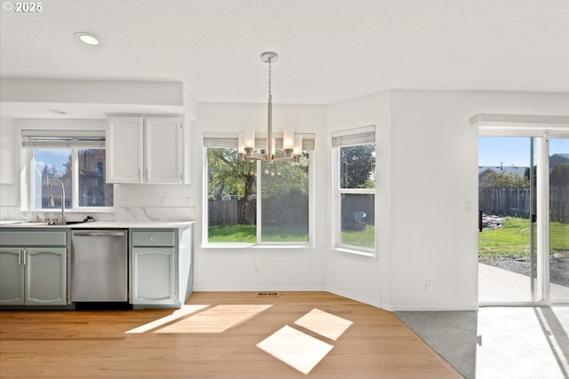 unfurnished dining area with a sink, visible vents, baseboards, light wood-type flooring, and a notable chandelier
