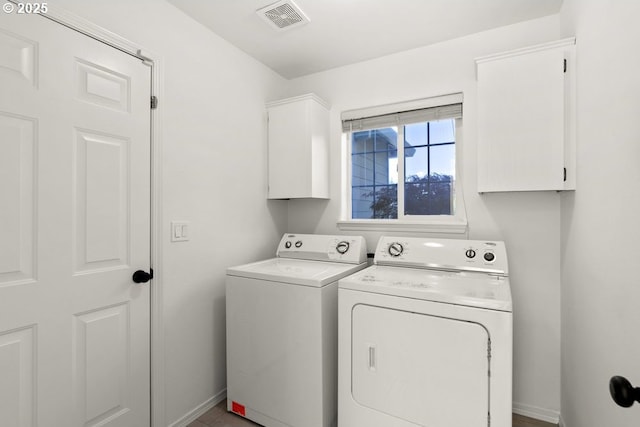 clothes washing area with cabinet space, independent washer and dryer, visible vents, and baseboards