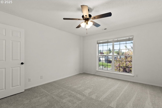 carpeted spare room with a ceiling fan, visible vents, and baseboards