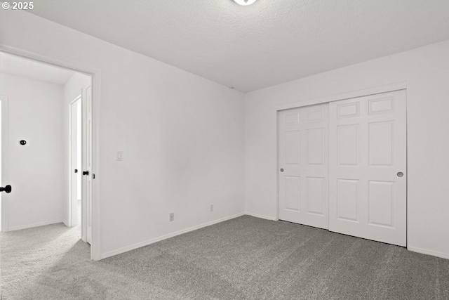 unfurnished bedroom featuring baseboards, a textured ceiling, a closet, and carpet