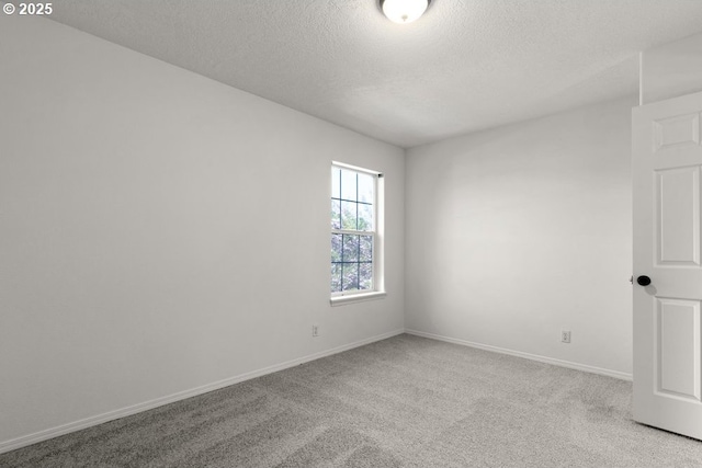 carpeted empty room featuring a textured ceiling and baseboards