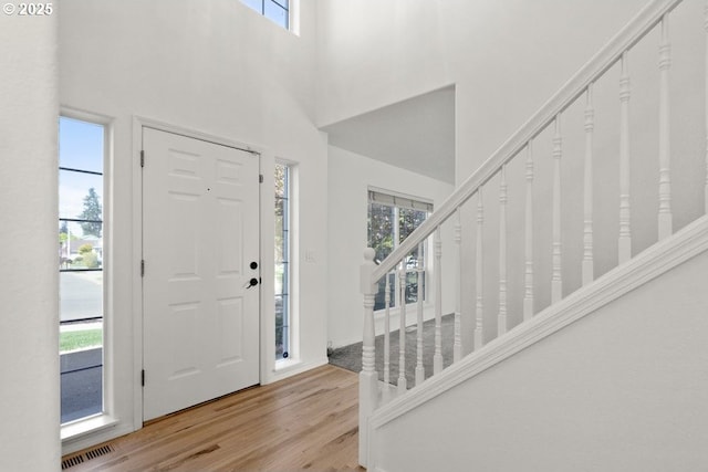 foyer entrance with stairs, visible vents, light wood-style floors, and plenty of natural light