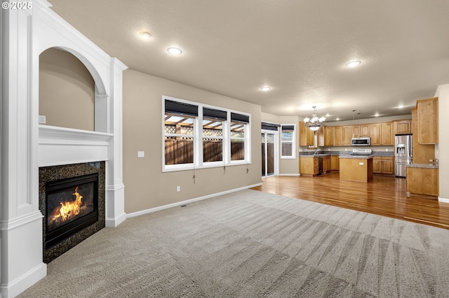 unfurnished living room featuring an inviting chandelier and light colored carpet