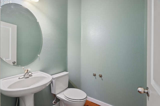 bathroom with toilet, baseboards, and a sink