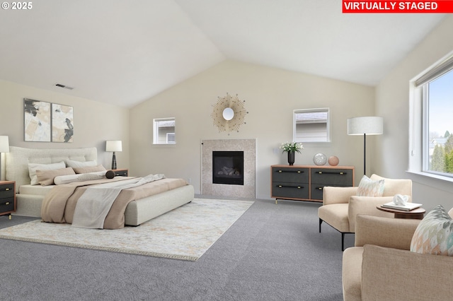 bedroom with visible vents, carpet floors, lofted ceiling, and a tiled fireplace