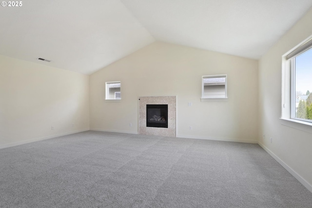 unfurnished living room with visible vents, light carpet, lofted ceiling, a tiled fireplace, and baseboards