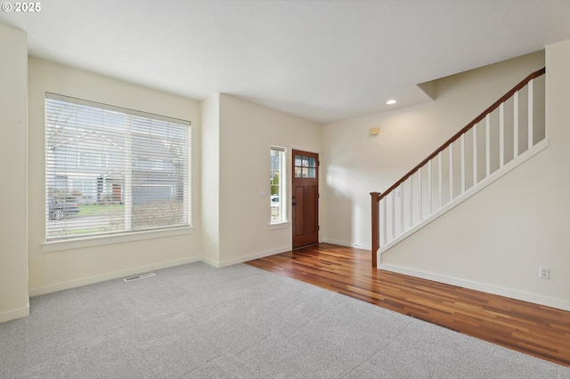 carpeted foyer with visible vents, baseboards, and stairs