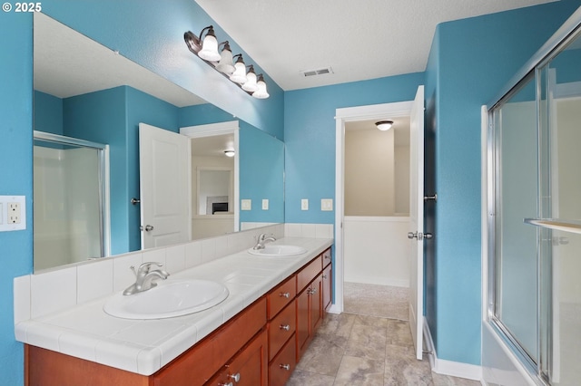 bathroom with an enclosed shower, visible vents, and a sink