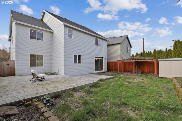 back of house featuring a lawn, a wooden deck, and fence