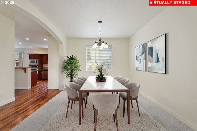 dining area featuring recessed lighting, baseboards, arched walkways, and a chandelier