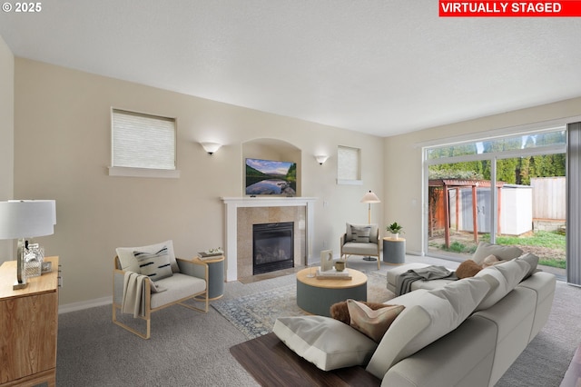 carpeted living area featuring baseboards, a textured ceiling, and a tile fireplace