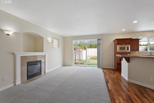 unfurnished living room featuring a textured ceiling, recessed lighting, baseboards, and a tile fireplace