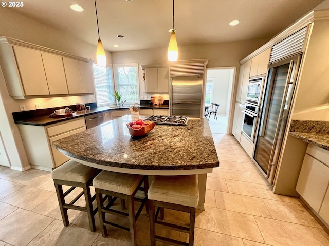 kitchen featuring a breakfast bar area, recessed lighting, built in appliances, pendant lighting, and a center island