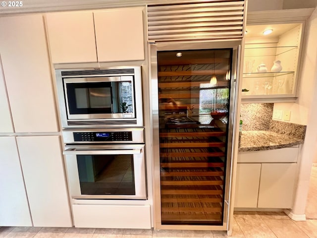 kitchen with light stone counters, stainless steel appliances, decorative backsplash, wine cooler, and white cabinetry