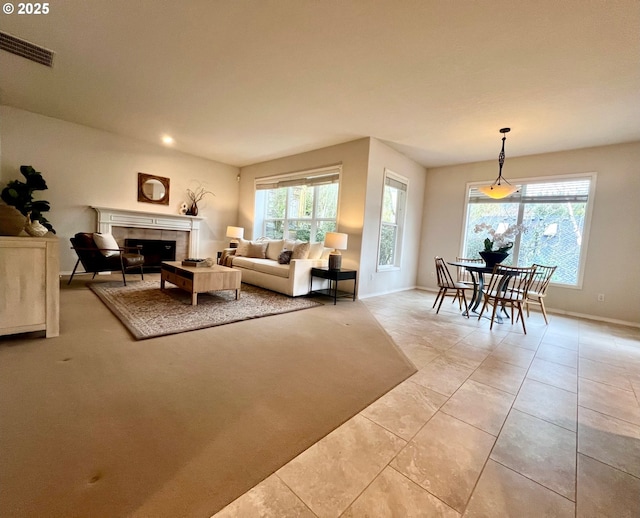 living room with a tiled fireplace, light tile patterned floors, baseboards, and visible vents