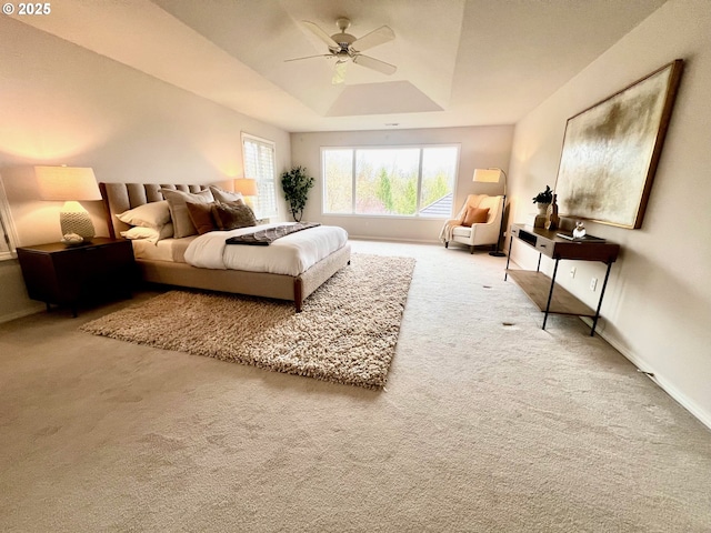 bedroom with ceiling fan, baseboards, a raised ceiling, and carpet