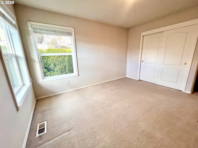 unfurnished bedroom with carpet flooring, visible vents, a closet, and baseboards