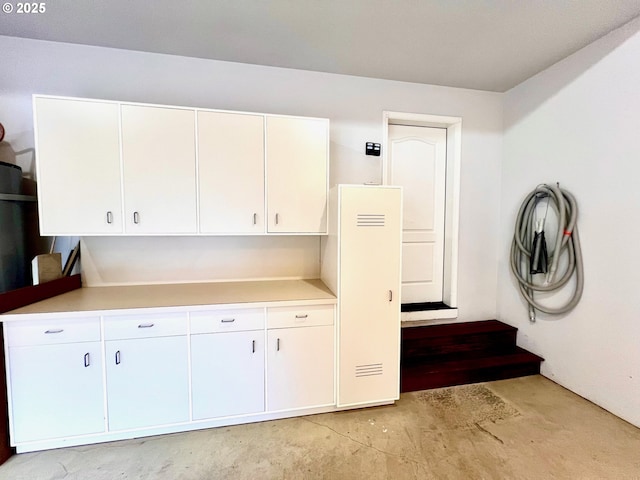 kitchen with white cabinets, unfinished concrete floors, and light countertops