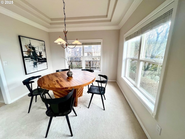 dining room with a raised ceiling, light colored carpet, baseboards, and ornamental molding