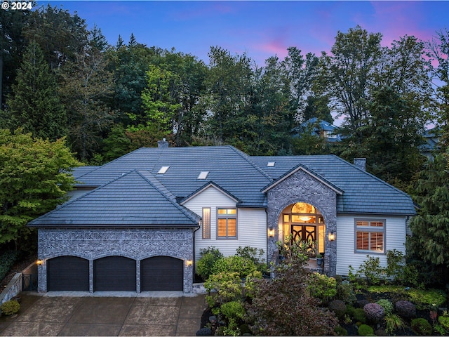 view of front of home with a garage, a chimney, and driveway