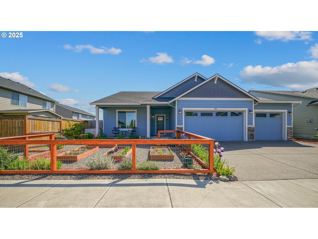view of front of home featuring an attached garage, driveway, fence private yard, and stone siding