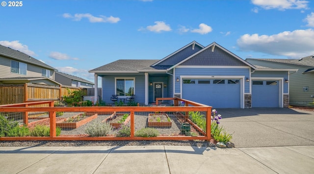 view of front of home featuring an attached garage, driveway, fence private yard, and stone siding