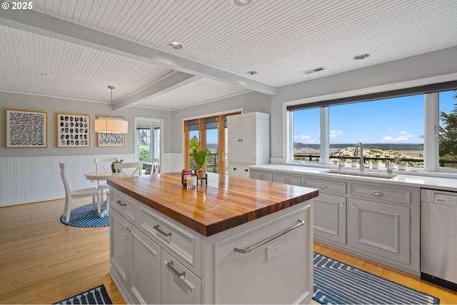 6413 Buena Vista Dr, Vancouver, WA 98661 - kitchen featuring butcher block counters, stainless steel dishwasher, a wainscoted wall, light wood-style flooring, and beamed ceiling