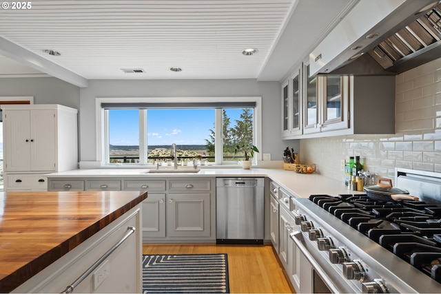 6413 Buena Vista Dr, Vancouver, WA 98661 - kitchen with appliances with stainless steel finishes, butcher block counters, extractor fan, light wood-style flooring, and glass insert cabinets